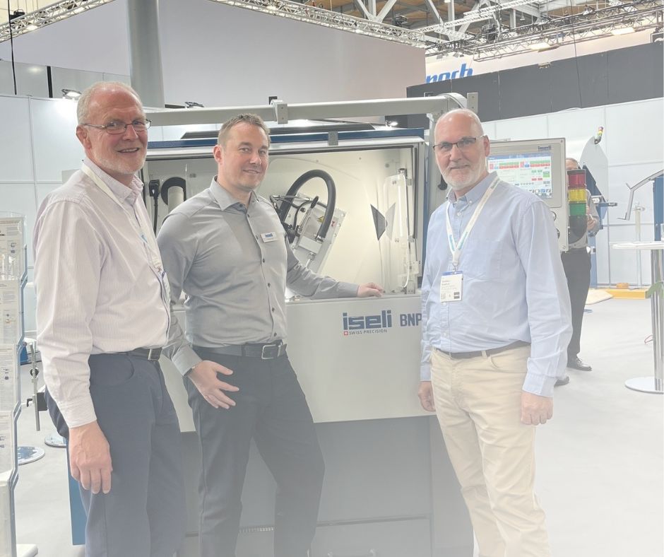 Two members of the team standing in front of the Iseli BNP machine on the Ligna show floor, smiling after a successful supplier meeting.