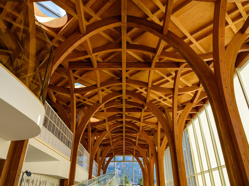 Interior view of a building with curved glulam timber arches and exposed wooden roof structure