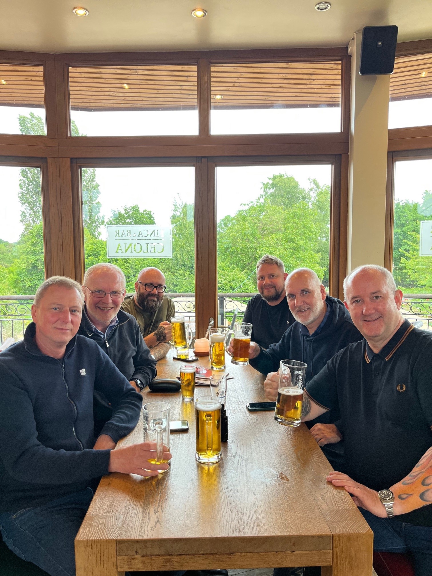 The full EPS team enjoying drinks together after Ligna 2025, seated around a table in a sunny German pub.