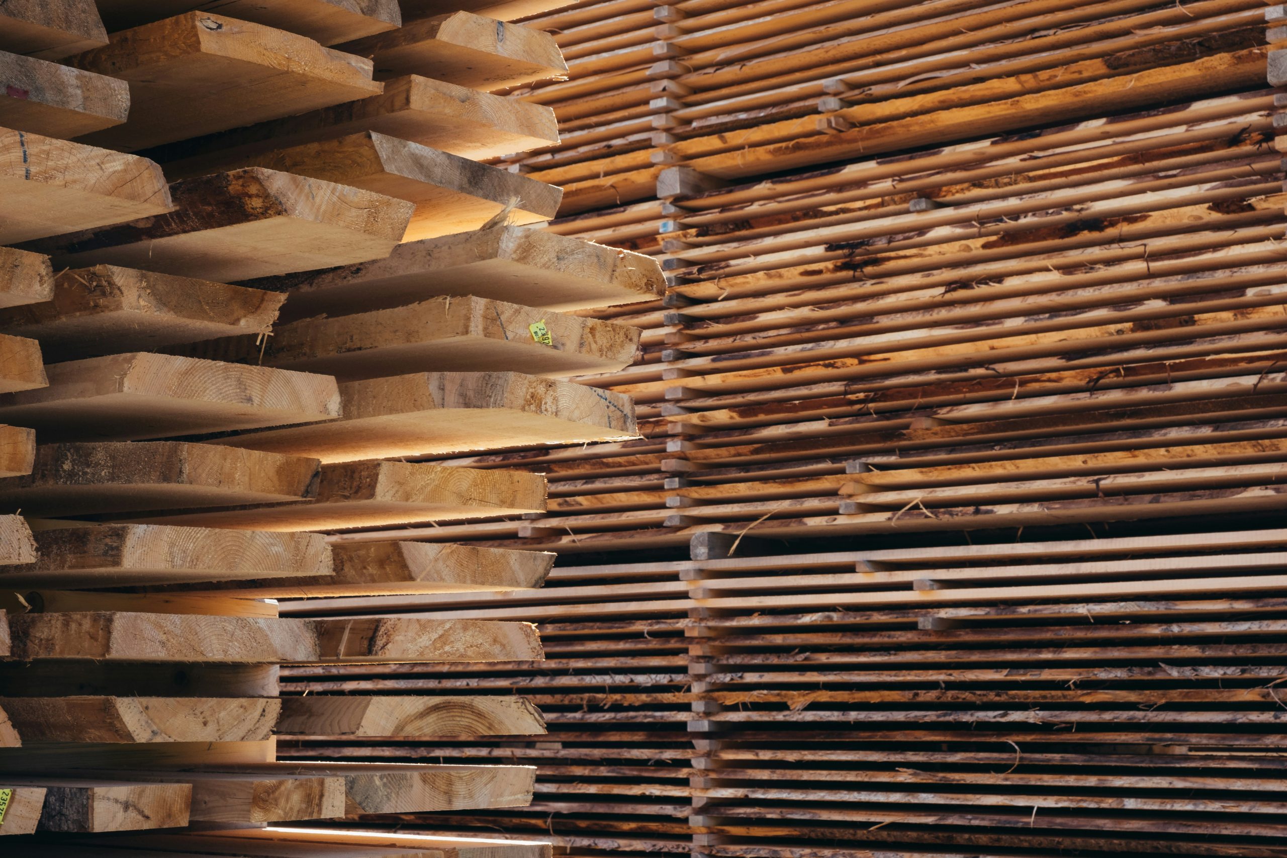 Two tidy stacks of timber planks in a sawmill, showing cleanly cut boards arranged in alternating layers; the organised piles emphasise precision cutting and efficient use of each log.